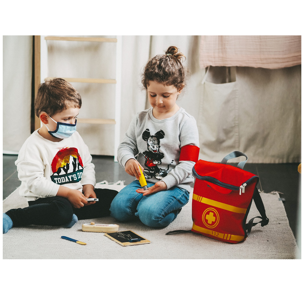 Zwei Kinder spielen mit dem Notarztrucksack Arzt; eines trägt eine Maske, während das andere den Spielzeug-Arztkasten und das Stethoskop verwendet.