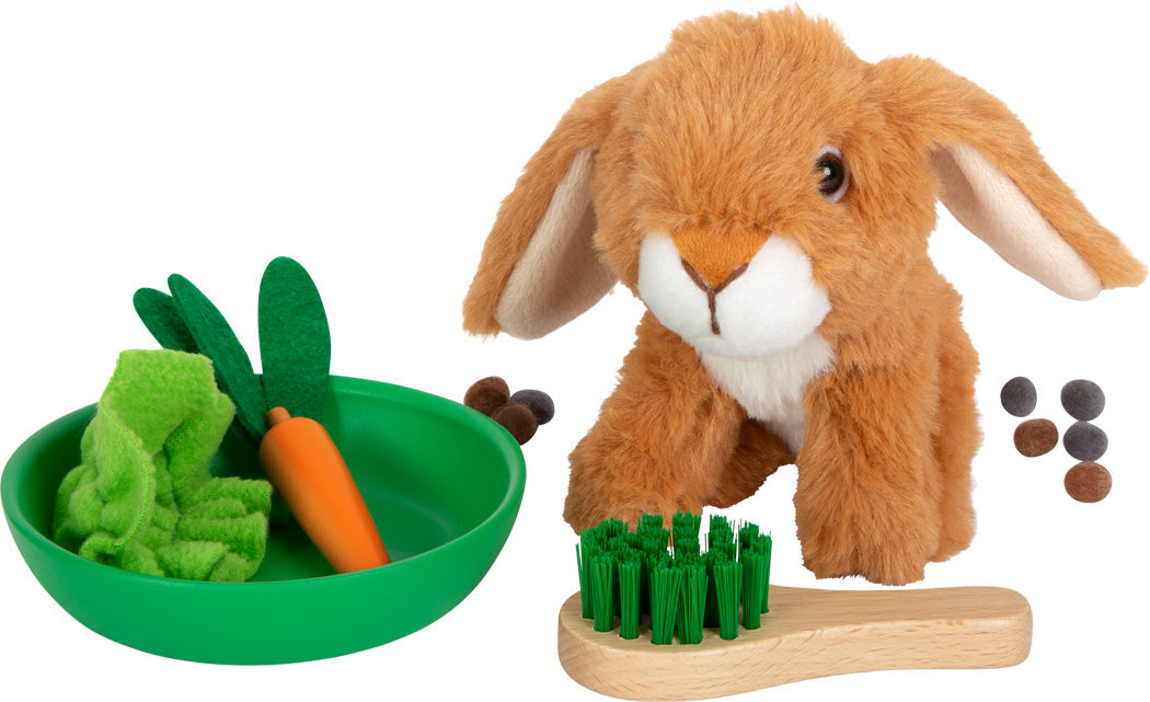 Hasenstall mit Auslauf enthält einen braunen Plüschhasen, eine Fellbürste, eine Spielzeugkarotte, eine grüne Schüssel und kleine braune und graue Bälle.