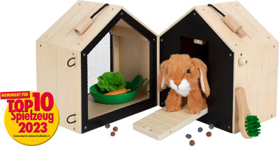Der Hasenstall mit Auslauf ist ein Spielzeug-Kaninchenstall aus Holz mit einem Plüschhasen, Spielzeuggemüse und einem Top 10 Spielzeug 2023-Award-Abzeichen.