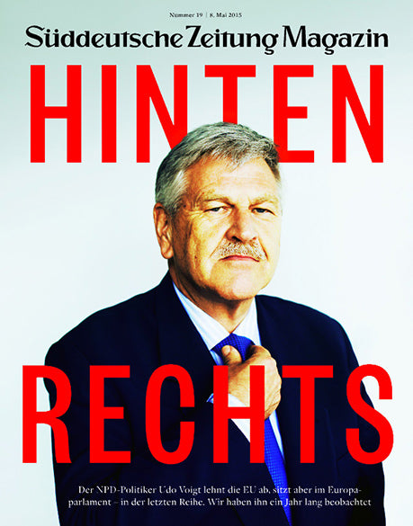 Ein Mann in Anzug und Krawatte posiert vor einem weißen Hintergrund mit großer roter Schrift: HINTEN RECHTS.