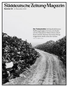 Schwarz-Weiß-Foto einer unbefestigten Straße zwischen großen Schrotthaufen; deutscher Text oben und an der Seite.