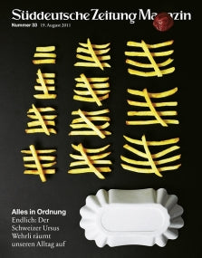 Pommes frites in ordentlichen Gittern neben einer weißen Seifenschale auf einem Zeitschriftenumschlag mit deutschem Text.