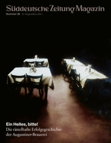 Zwei leere, weiß gedeckte Tische in einem schwach beleuchteten Raum auf dem Cover des Süddeutsche Zeitung Magazins.