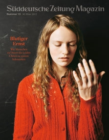 Eine junge Frau in einem roten Pullover betrachtet ihre Hand vor einem dunklen Hintergrund auf dem Cover einer Zeitschrift.