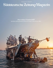 Menschen stehen auf einem selbstgebauten, mit Fahnen geschmückten Floß, das bei Sonnenuntergang auf dem Wasser treibt.