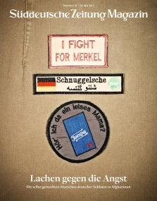 Zeitschriftenumschlag mit drei gestickten Aufnähern auf Stoff, darunter I FIGHT FOR MERKEL und eine deutsche Flagge.