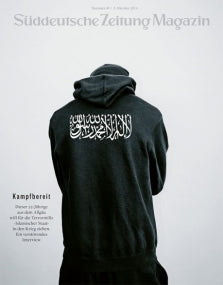 Eine Person in einem schwarzen Kapuzenpullover mit arabischen Schriftzeichen auf dem Rücken, die von der Kamera wegschaut.