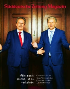 Zwei Männer in blauen Anzügen stehen mit offenen Armen vor einer Holztür, Titelbild Süddeutsche Zeitung Magazin.