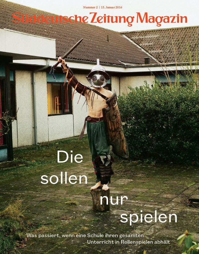 Eine kostümierte Person steht mit einem Stock in der Hand auf einem Baumstumpf auf dem Schulhof. Ein deutscher Text überlagert das Bild.