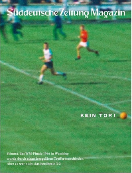 Ein unscharfes Bild eines Fußballspiels mit dem Ball in der Nähe der Torlinie und deutschem Text überlagert.