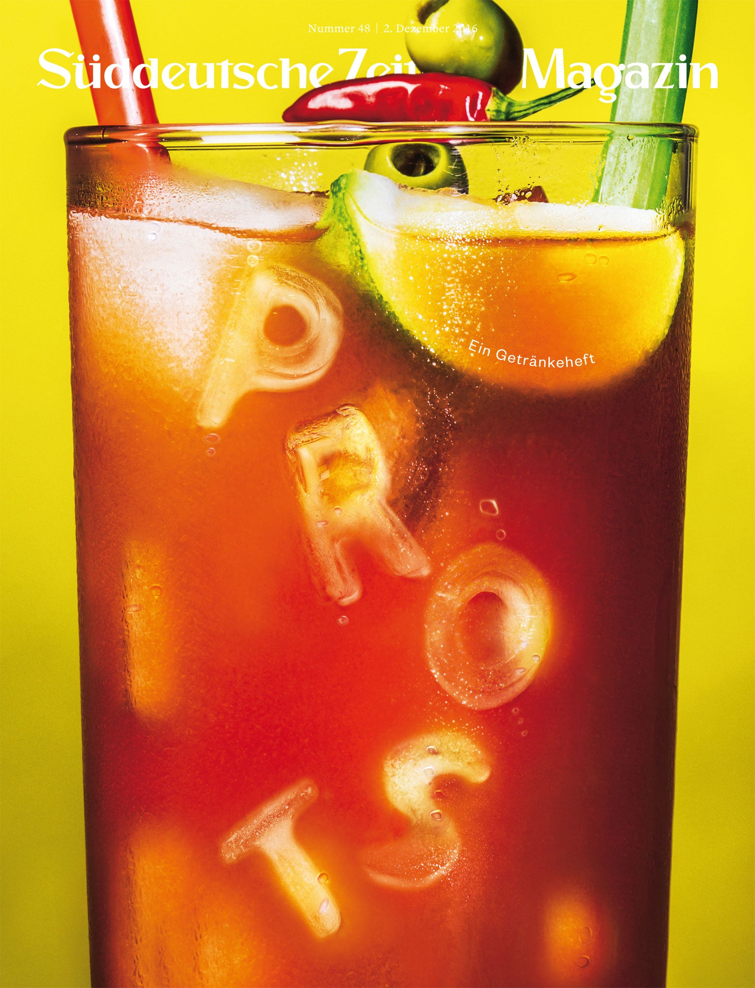 Ein Glas mit einem eisgekühlten Cocktail mit Limette, Oliven und Eiswürfeln mit der Aufschrift PROST vor einem gelben Hintergrund.