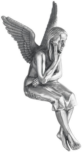 Silberne Engelsfigur mit Flügeln, sitzt und stützt das Kinn auf die Hand, scheint in Gedanken versunken.