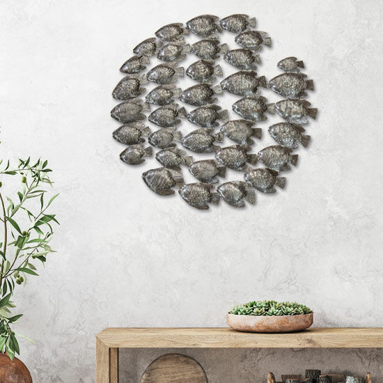Metallwandkunst eines Fischschwarms über einem Holztisch mit einer Pflanze und einer Schale mit Sukkulenten.