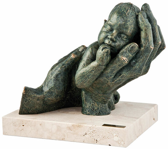 Skulptur großer Hände, die sanft ein schlafendes Baby wiegen, ausgestellt auf einem Steinsockel.