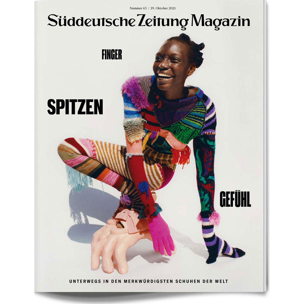 Eine lächelnde Frau in farbenfroher Strickkleidung und einzigartigen Schuhen posiert auf dem Cover des Süddeutsche Zeitung Magazins.