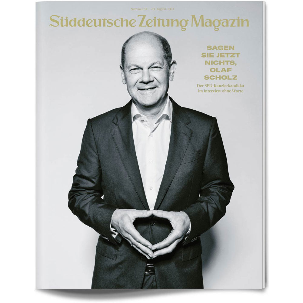 Lächelnder Mann im Anzug, der mit seinen Händen eine Raute formt, auf dem Cover des Süddeutsche Zeitung Magazins.