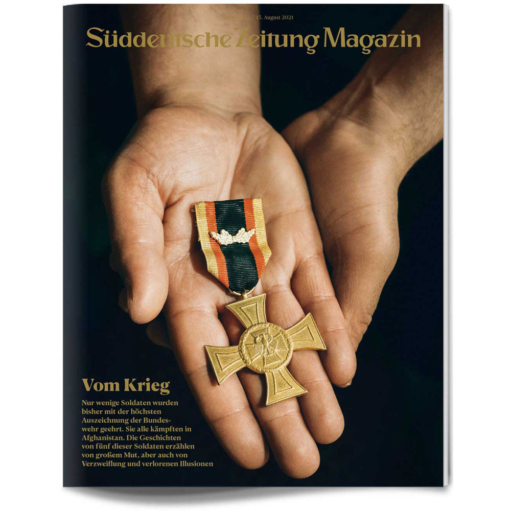Eine Person hält eine militärische Medaille und ein Band in ihren offenen Händen vor einem schwarzen Hintergrund.