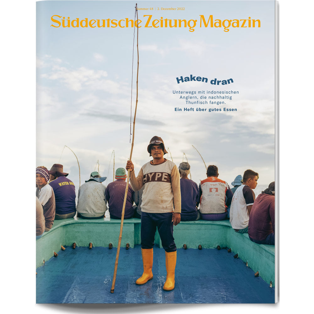 Ein Mann steht auf einem Boot und hält eine Angel, umgeben von Fischern, die auf dem Bootsrand sitzen.