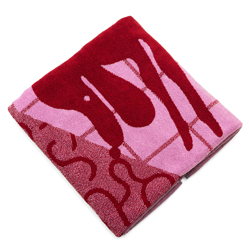 Gefaltetes Handtuch mit einem abstrakten Muster in Rot und Rosa, mit Tropfen und Wellenlinien.