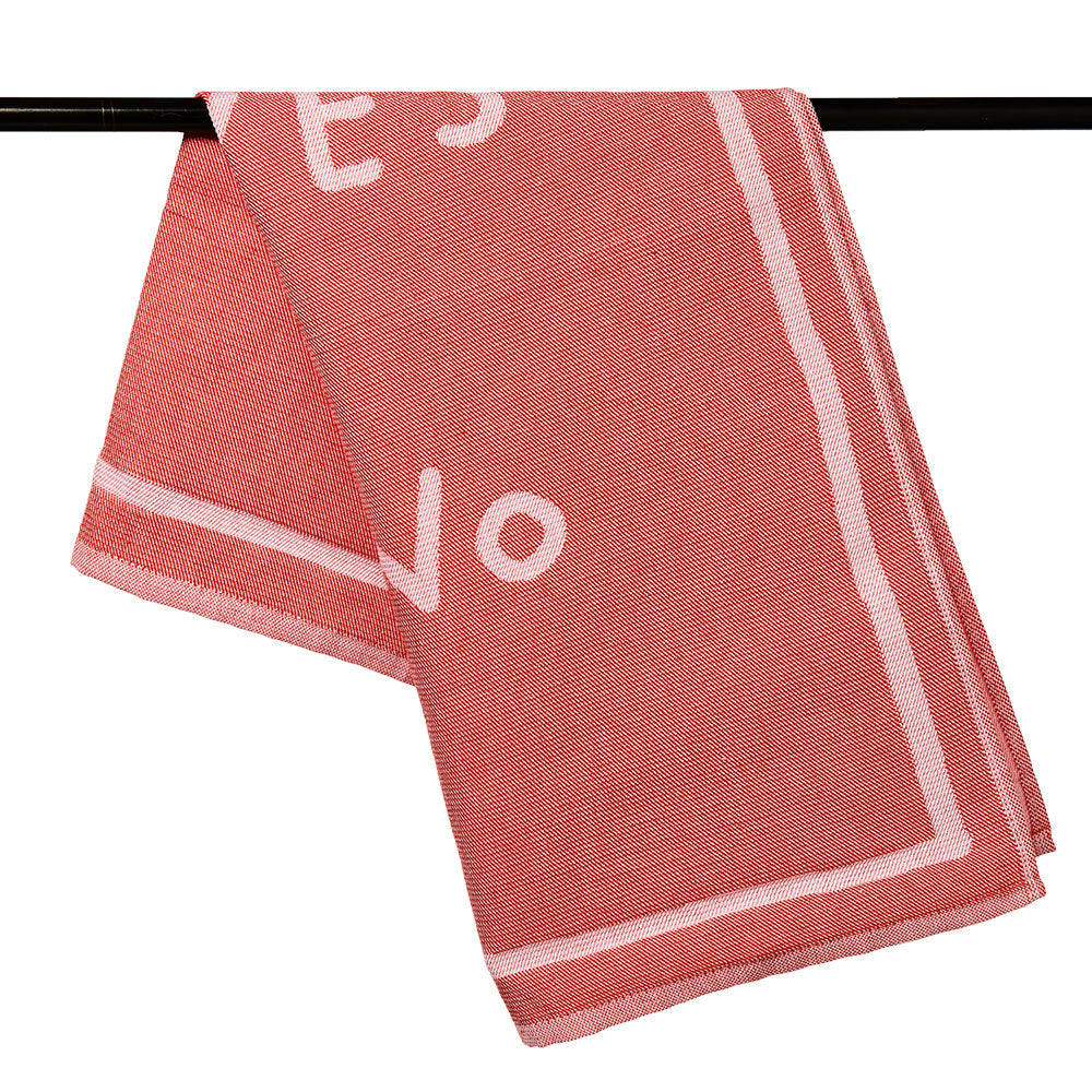 Ein gefaltetes rotes Handtuch mit weißem Text und weißem Rand, über eine schwarze Stange drapiert.