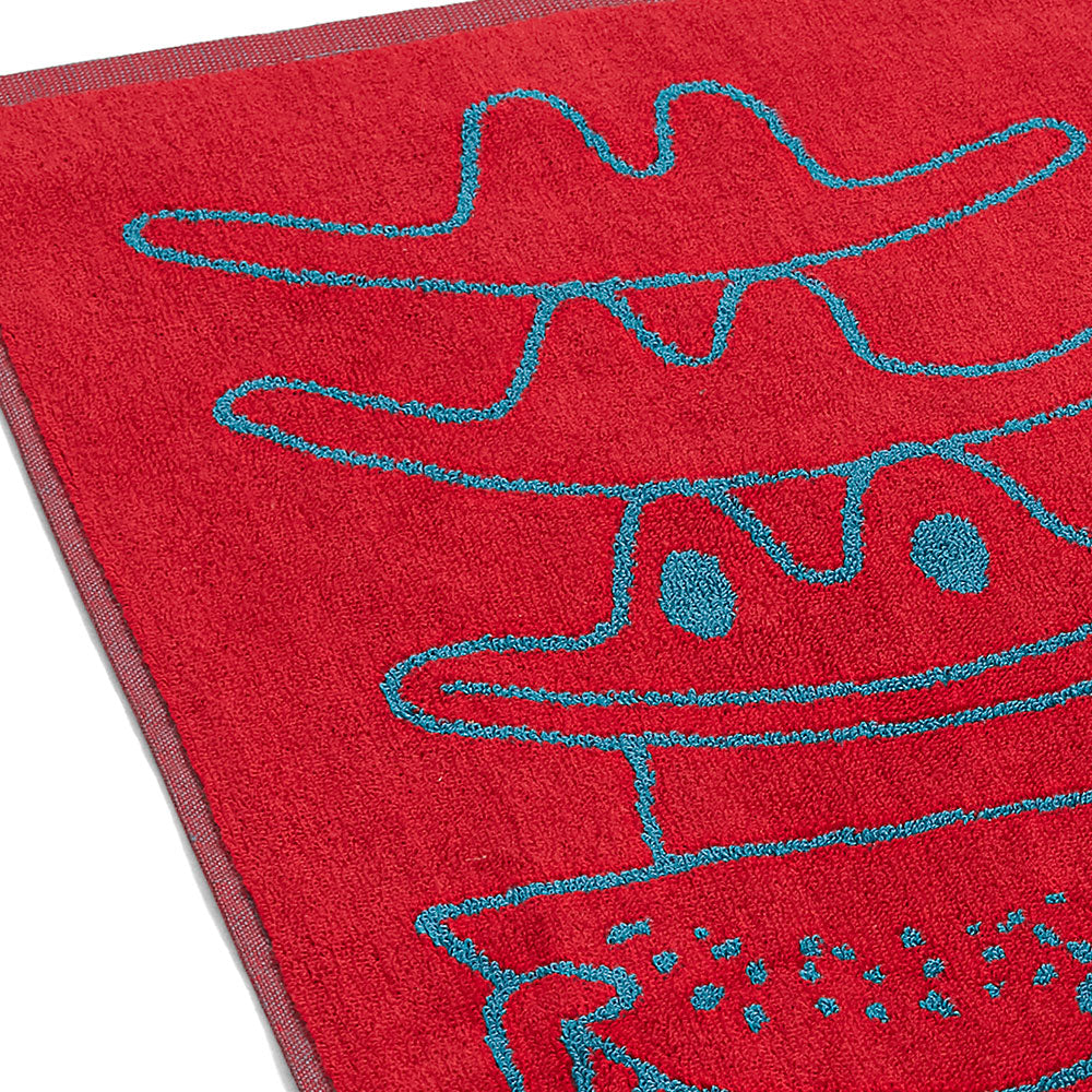 Rotes Handtuch mit blauen Strichzeichnungen von verspielten, abstrakten Gesichtern mit Hüten.