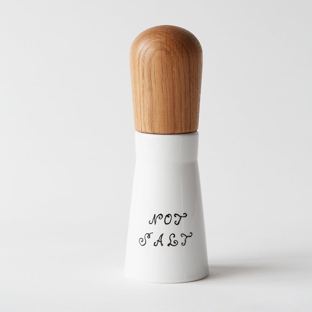 Gewürzmühlen-Set „Nicht Salz, nicht Pfeffer“ in einem weißen Behälter mit Holzdeckel und dekorativer Schrift, abgebildet auf schlichtem Hintergrund.