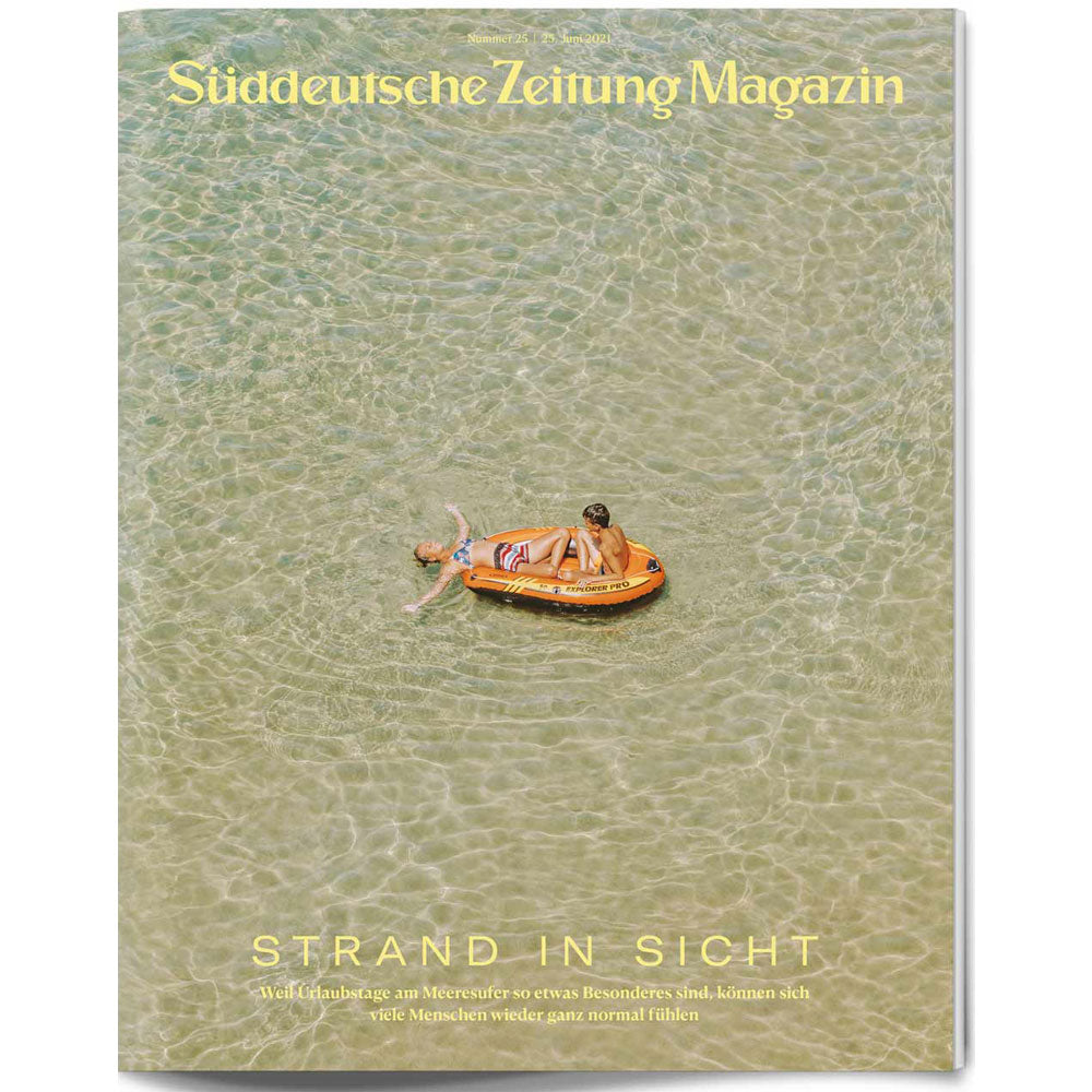 Zwei Personen entspannen sich in einem kleinen Schlauchboot in klarem, flachem Wasser, von oben gesehen.