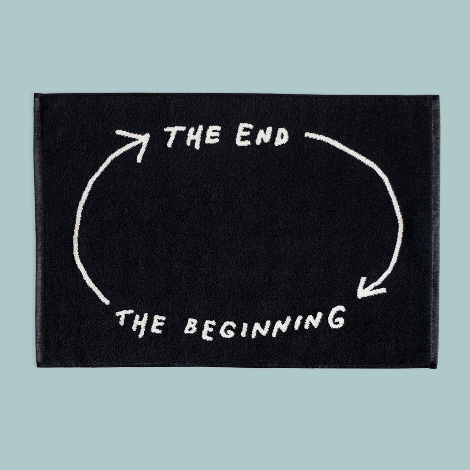 Eine schwarze Matte mit weißen Pfeilen und dem Text „DAS ENDE“ und „DER ANFANG“ in einer Endlosschleife.