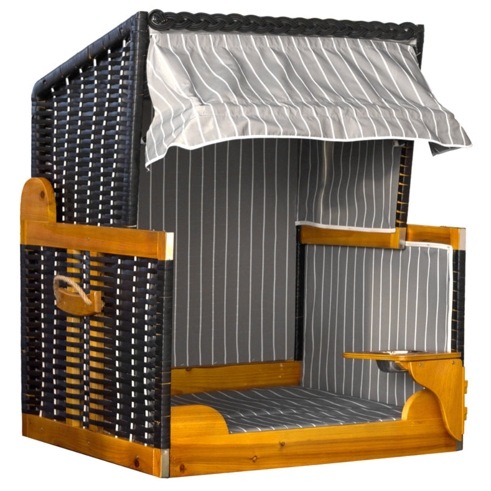 Ein Strandkorb aus Weidengeflecht und Holz mit einziehbarem, gestreiftem Sonnendach, seitlichen Armlehnen und integriertem, klappbarem Tablett.