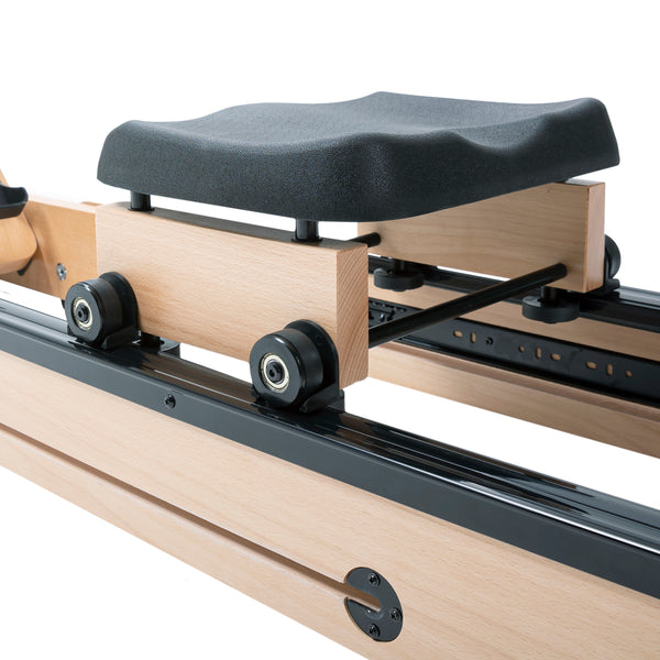 Nahaufnahme eines Rudergerätsitzes mit schwarzen Rädern auf einer Bahn aus hellem Holz und schwarzem Metall.