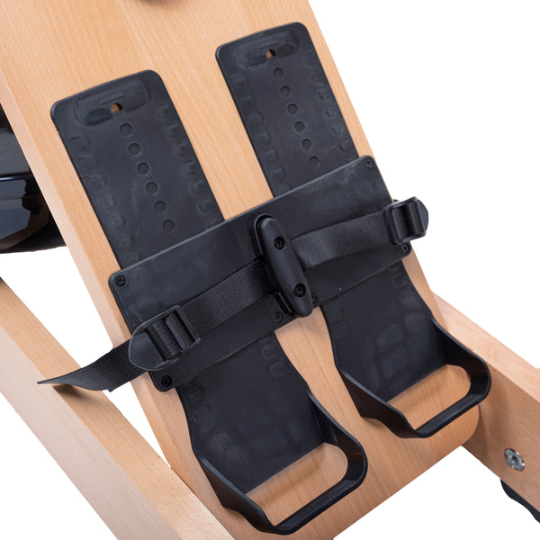 Nahaufnahme von verstellbaren schwarzen Fußstützen mit Riemen an einem hölzernen Rudergerät.