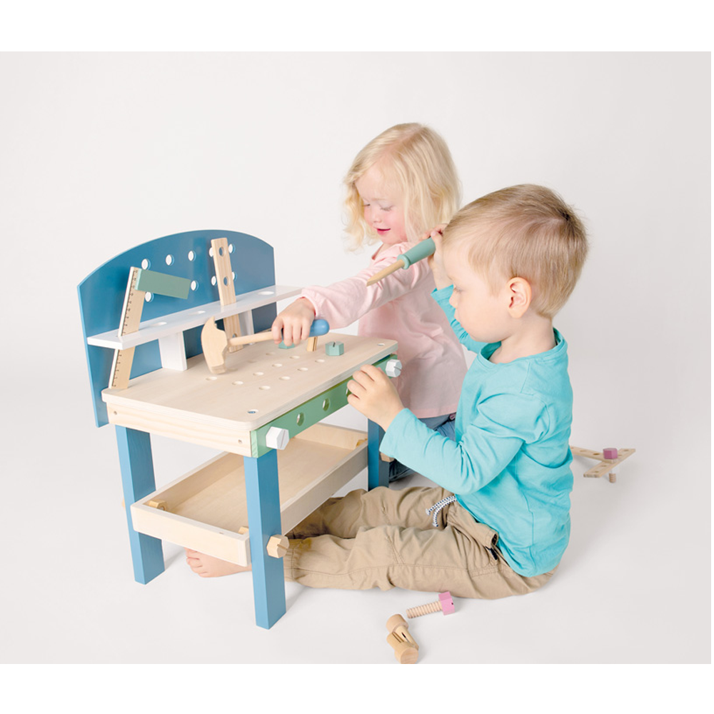 Zwei kleine Kinder spielen mit der Werkbank kompakt „Nordic“, einer Holzspielzeugwerkbank und Werkzeugen auf weißem Hintergrund.