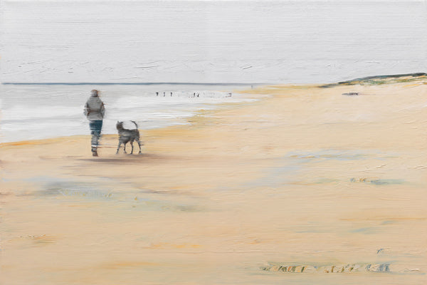 Eine Person und ein Hund gehen unter einem bewölkten Himmel an einem ruhigen Sandstrand entlang.