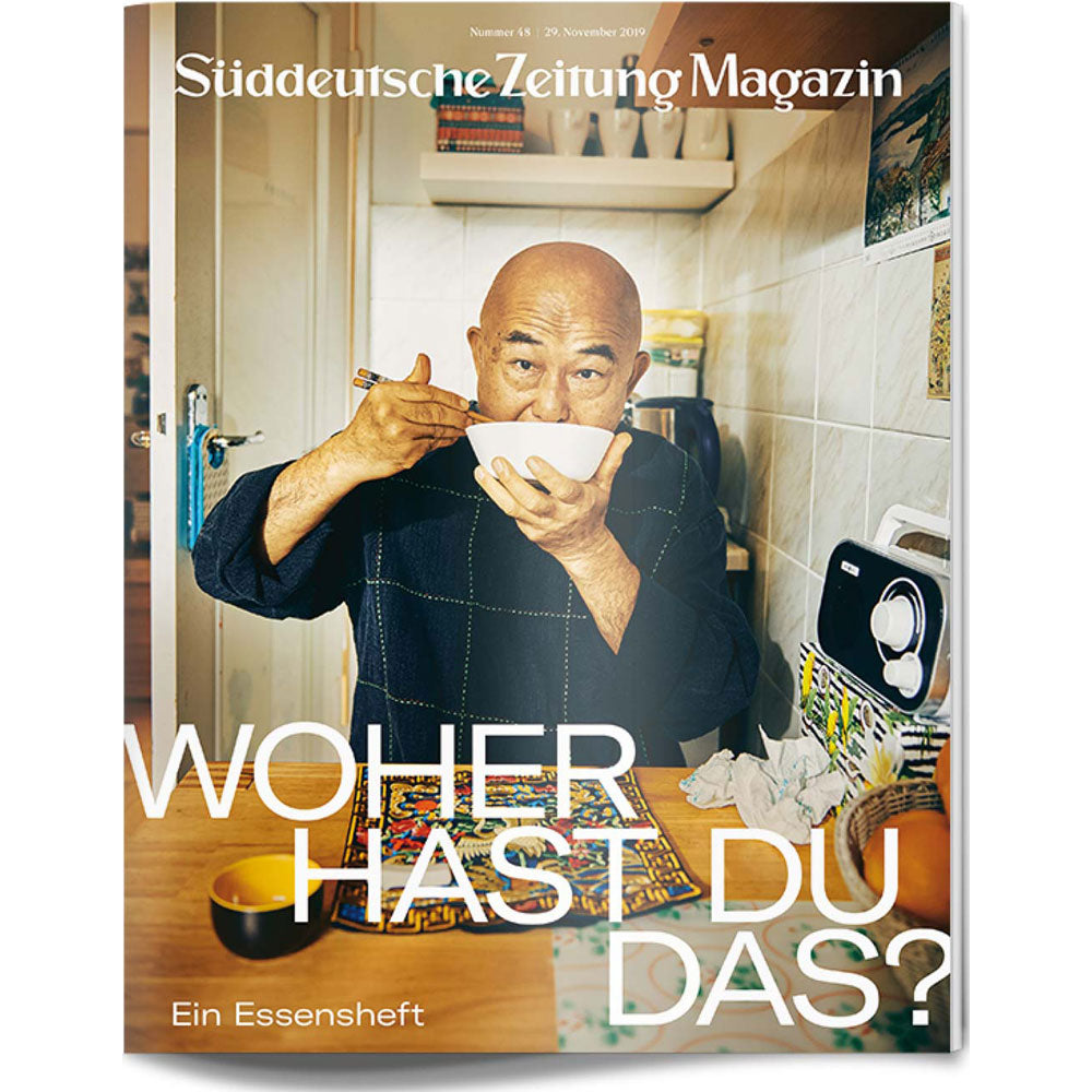 Glatzköpfiger Mann isst Nudeln mit Stäbchen in einer kleinen Küche, Titeltext des Süddeutsche Zeitung Magazins überlagert.