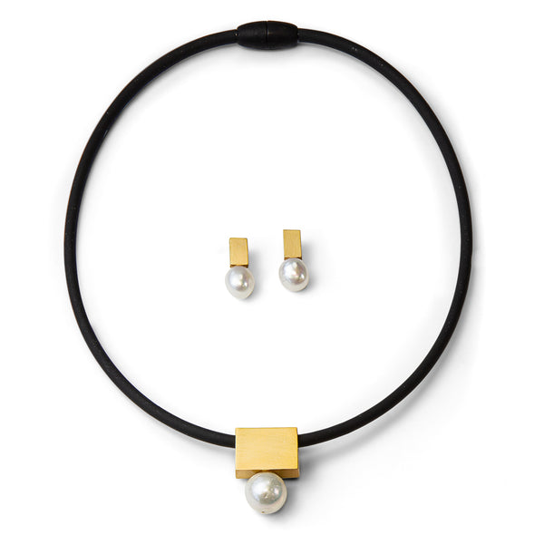 Schwarze Halskette mit goldenem Quadrat und Perle, passende Ohrstecker aus Gold und Perle auf weißem Hintergrund.