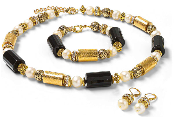 Halskette, Armband und passende Perlenohrringe aus Gold, Schwarz und Perlen auf weißem Hintergrund.