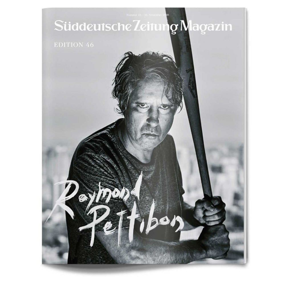 Schwarz-weißes Titelbild eines Magazins mit einem ernsten Mann, der einen Baseballschläger hält, mit dem Titel Raymond Pettibon.