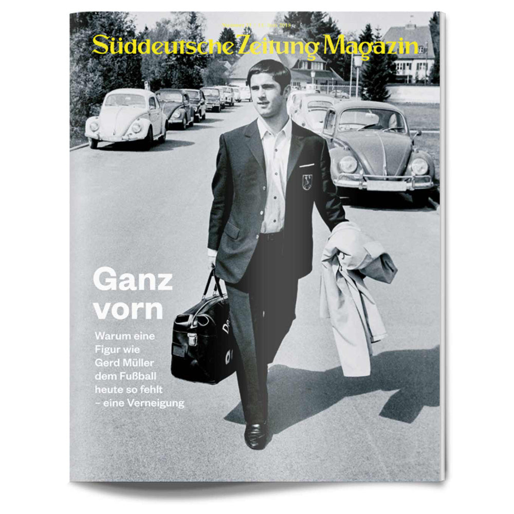 Ein Mann im Anzug spaziert mit einer Sporttasche vor einem Oldtimer auf dem Titelbild einer Zeitschrift.