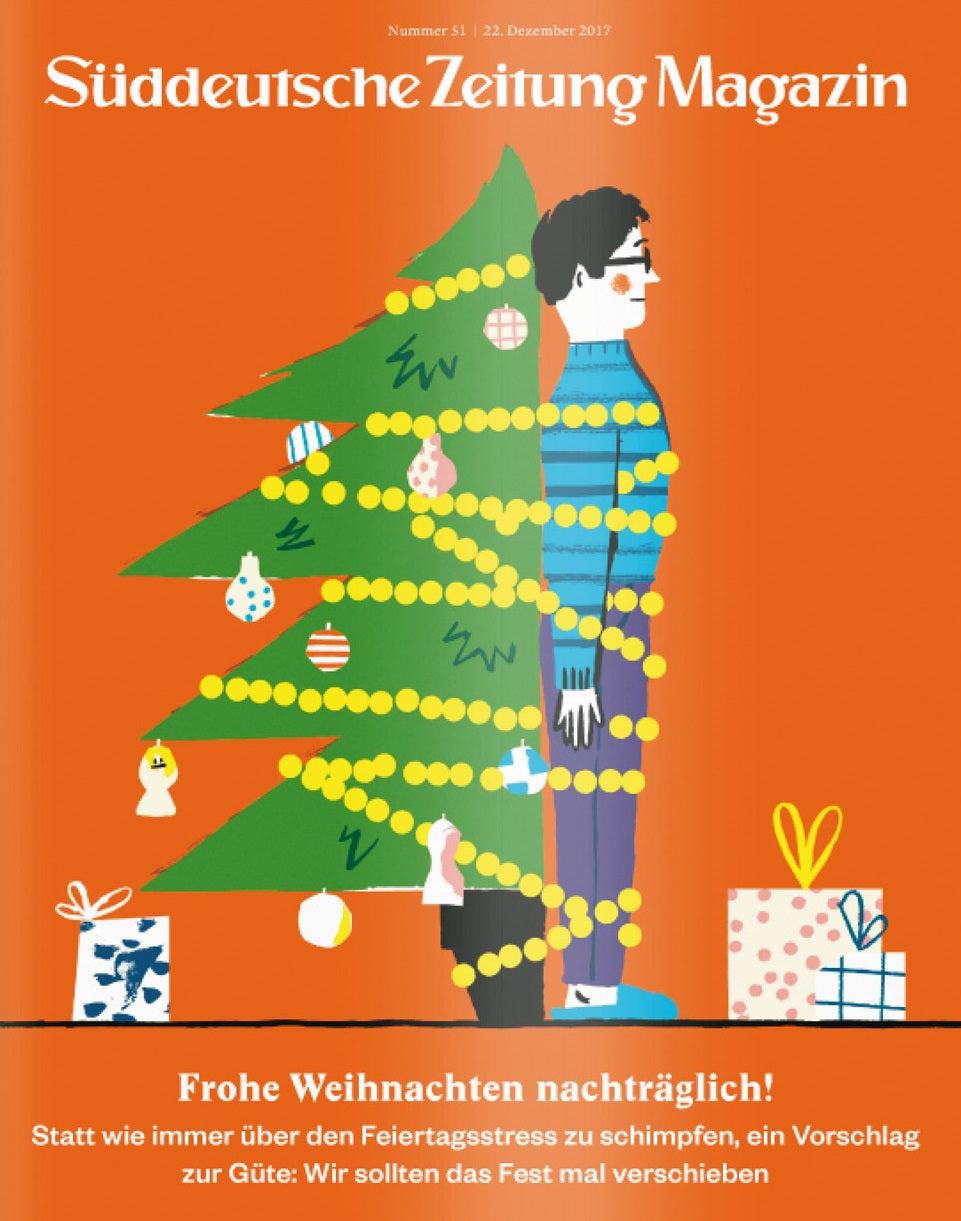Ein Mann steht hinter einem Weihnachtsbaum, der mit Lichtern umhüllt ist, und auf dem Boden liegen Geschenke.